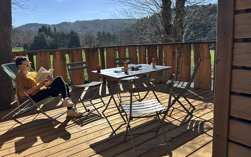 The Roulotte terrace with a stunning view of the river, unique accommodation in Haute-Loire, for rent at Les Murmures du Lignon campsite